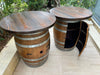 Two wooden barrel tables on a patio with outdoor furniture in the background.