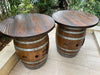 Two wooden barrel tables on a patio with greenery in the background
