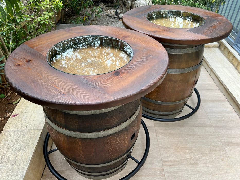 Two wooden barrel planters on a patio with plants in the background