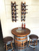 Wooden barrel table with wine bottles and stools against a wall with wine bottle racks.