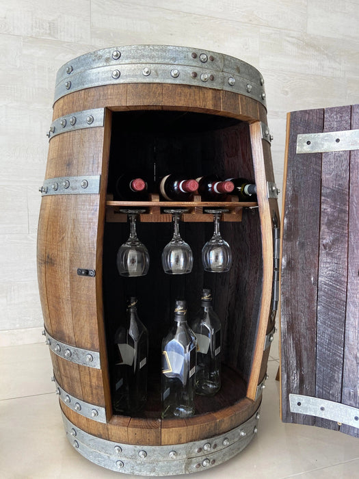 Wooden barrel with interior shelves holding wine bottles and glasses against a light background