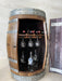 Wooden barrel with interior shelves holding wine bottles and glasses against a light background