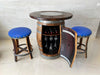 Wooden barrel bar with wine bottles and glasses, accompanied by two blue cushioned stools.