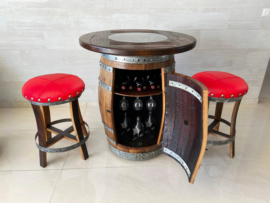 Wooden barrel table with wine storage and red cushioned stools in a room.