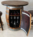 Wooden barrel-style bar table with wine bottles and glasses inside, on a tiled floor.