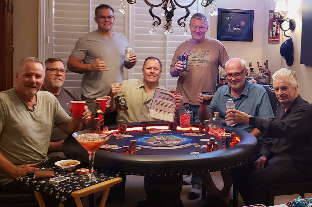 Group of men around a poker table in a casual setting