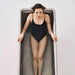 Woman in a black swimsuit standing inside a rectangular pool.