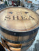 Wooden barrel with 'SHEA' engraved on it in a workshop setting