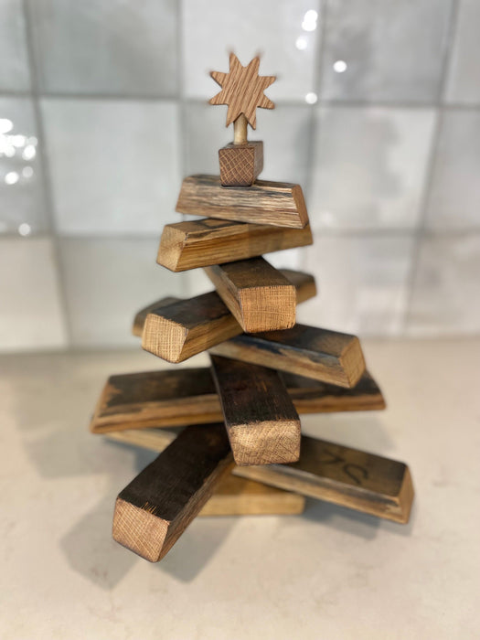 Wooden Christmas tree with star topper on a reflective surface