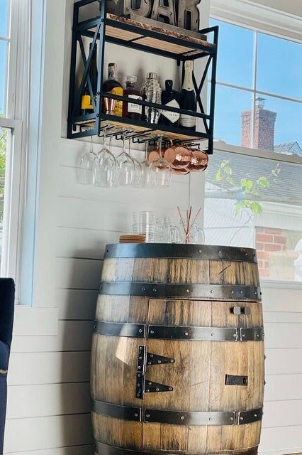 Wooden barrel bar with hanging shelf and glasses indoors