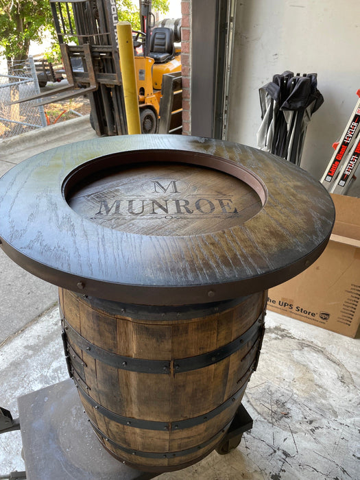 Wooden barrel table with 'M Munroe' engraving in an outdoor setting.