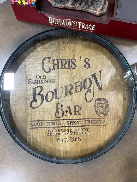 Personalized bourbon barrel head with engraved text on a wooden surface.