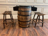 Wooden barrel table with two stools on a wooden floor.