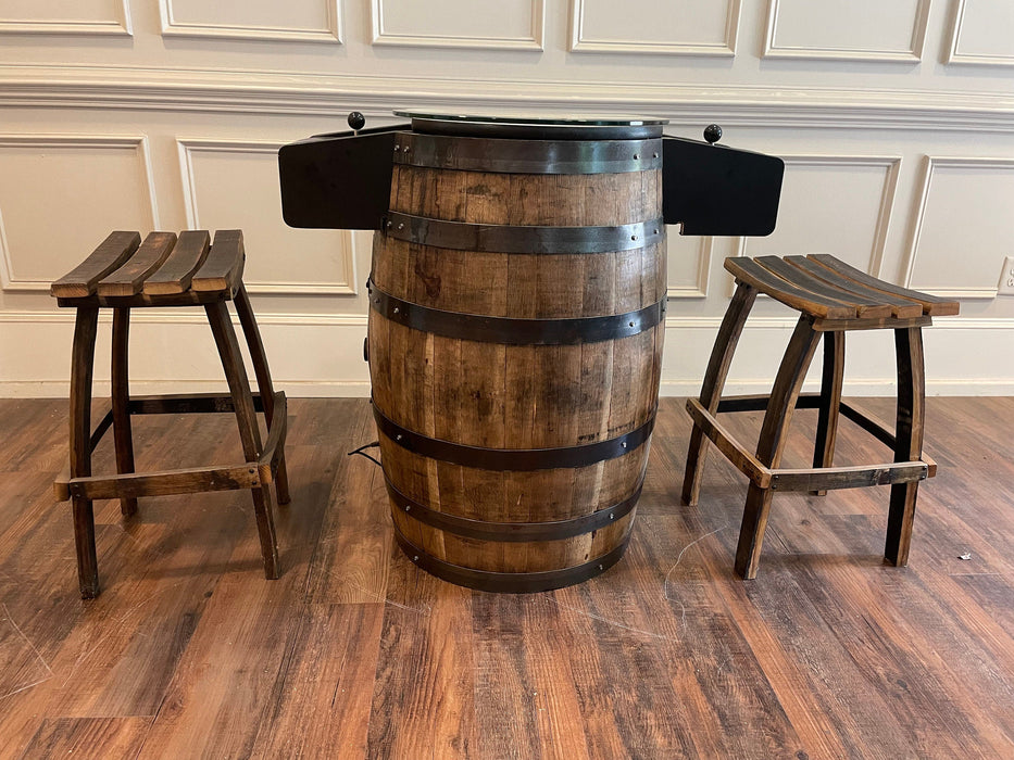 Wooden barrel table with two stools on a wooden floor.