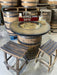 Wooden barrel table with stools and decorative items in a warehouse setting