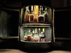 Bar cabinet with illuminated interior displaying various bottles of alcohol.