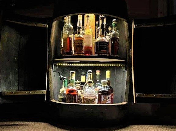 Bar cabinet with illuminated interior displaying various bottles of alcohol.