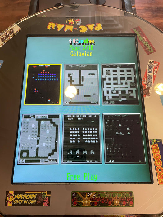 Multicade arcade machine displaying 'Galaxian' with various game screens on a wooden floor.