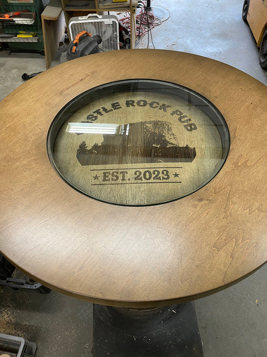 Wooden table with a glass inset displaying 'Castle Rock Pub' and 'Est. 2023'.