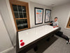 Boy playing air hockey in a room with framed pictures on the wall.