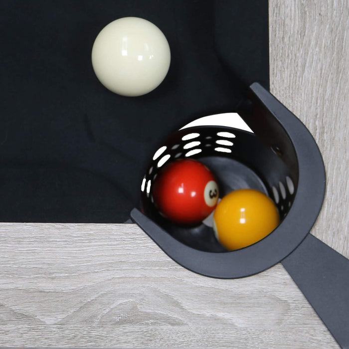 Pool balls in a pocket of a pool table with a white ball above.