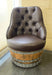 Brown leather chair on a wooden barrel base in a room with tiled floor and wall.