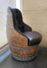 Chair made from a repurposed wine barrel with black cushioned seat against a neutral wall.