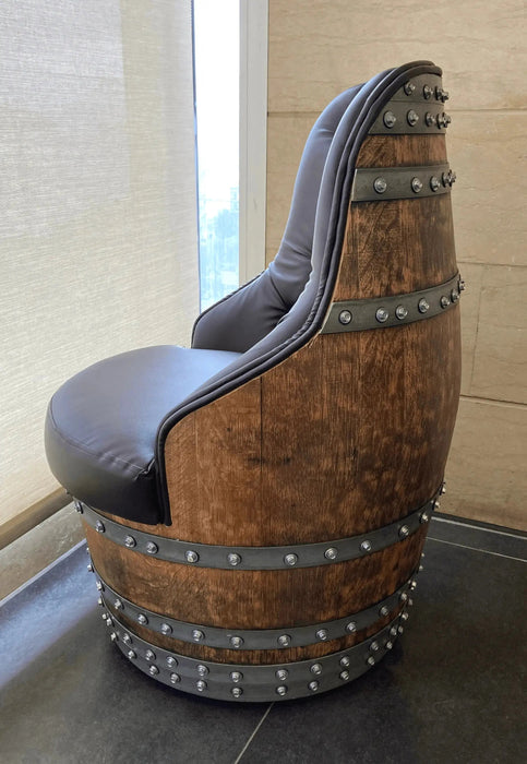 Chair made from a wooden barrel with metal bands and gray cushioned seat in a room.