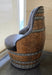 Chair made from a wooden barrel with metal bands and gray cushioned seat in a room.