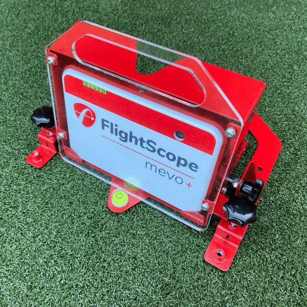 Red and clear device with 'FlightScope mevo+' branding on a green grass background