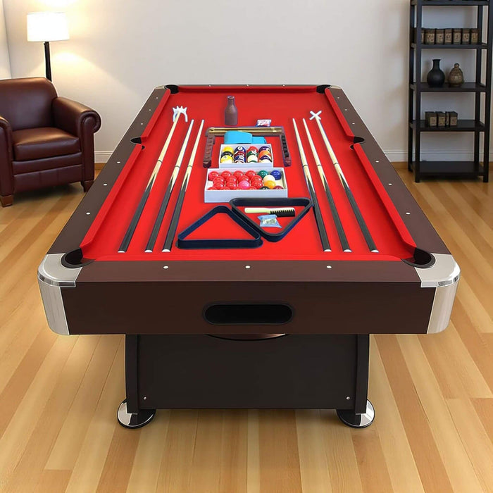 Pool table with red felt surface and pool cues on a wooden floor.