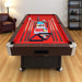 Pool table with red felt surface and pool cues on a wooden floor.