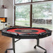 Round poker table with red and black surface in a room with large windows.