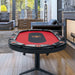 Poker table with red felt surface and black leather edges in a modern living room.