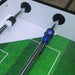Close-up of a table football (pocket soccer) table with green playing surface and metal rods.