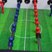 Close-up of table football rods with red and blue ends on a green playing field.
