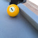 Yellow pool ball with number one on a blue felt pool table
