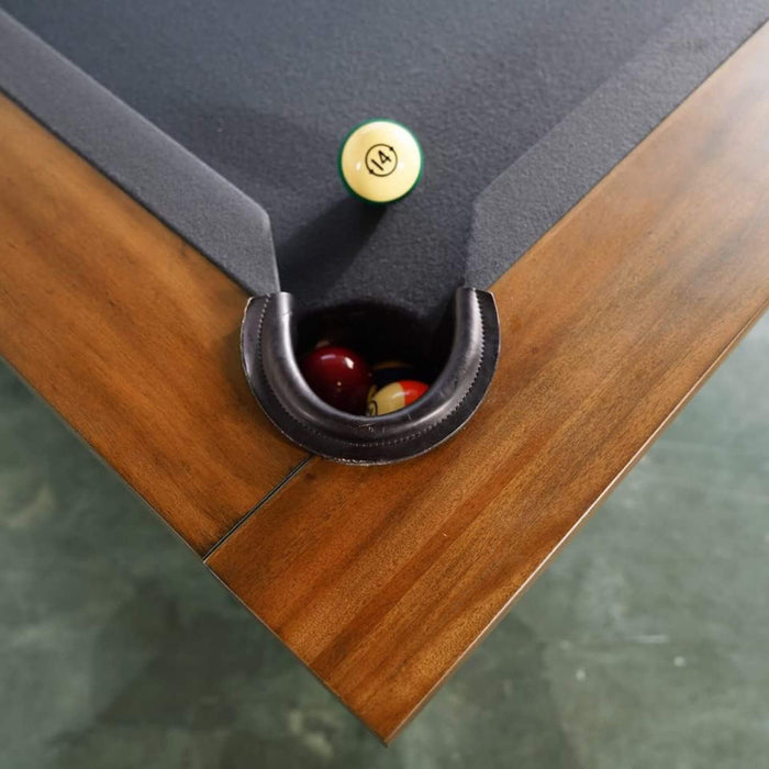 Close-up of a pool table with balls and a pocket.