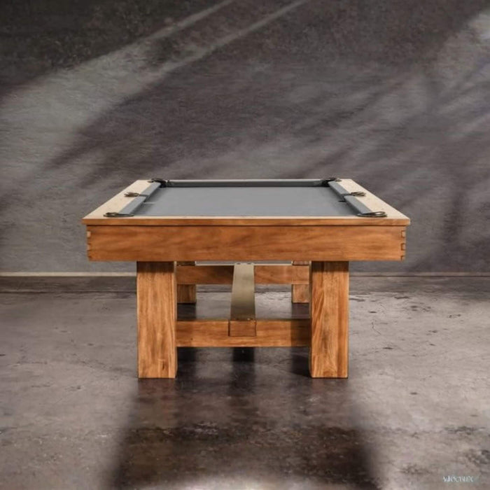 Wooden pool table with a gray felt surface on a dark concrete floor.