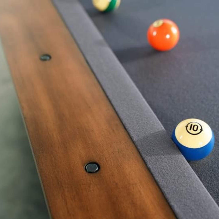 Close-up of a pool table with balls and a cue stick.