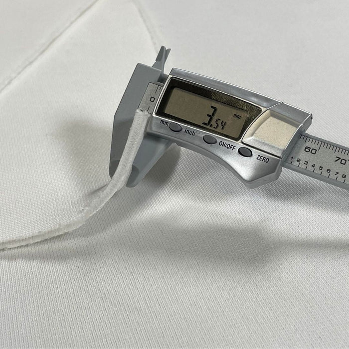 Digital caliper measuring a white fabric with a digital display showing a measurement.