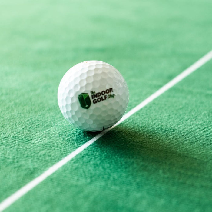 Golf ball with 'The Indoor Golf Shop' logo on a green surface