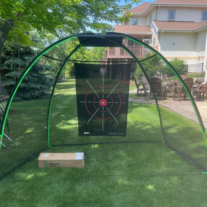 Golf practice net with a target board on a grassy area outdoors.