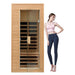 Woman standing next to a wooden sauna with glass door on a white background