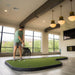 Person playing indoor putting green in a modern room with large windows.