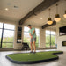 Man playing mini golf indoors with large windows and modern decor.
