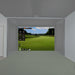 Golf simulator setup in a room with a screen displaying a golf course.