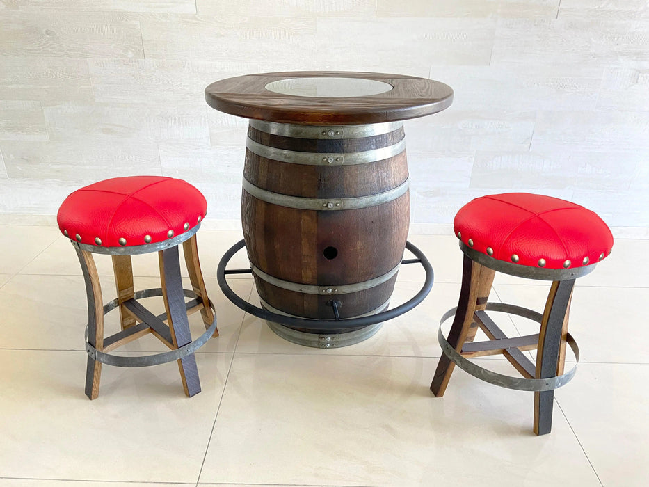 Barrel table with two red cushioned stools on a light tiled floor.