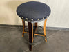 Bar stool with a dark gray cushioned seat and wooden legs on a tiled floor.