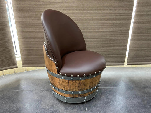 Chair made from a wine barrel with brown leather seats against a neutral wall.